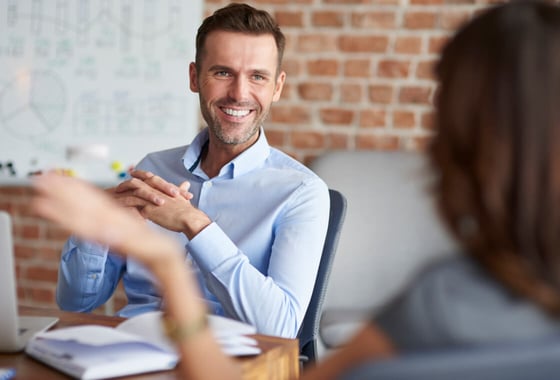 smiling man in front of a woman talking